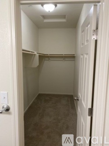 A small, empty room with a door on the left and a light switch on the wall.