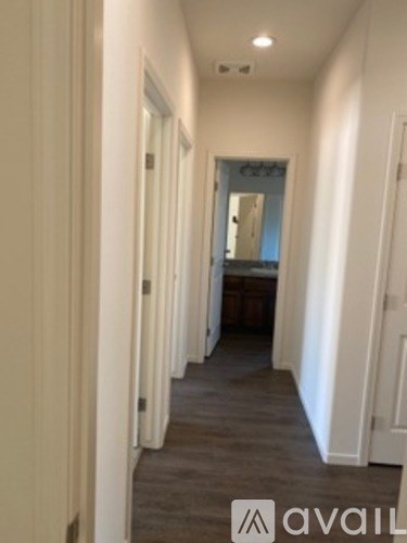 A hallway with a carpeted floor and white walls.