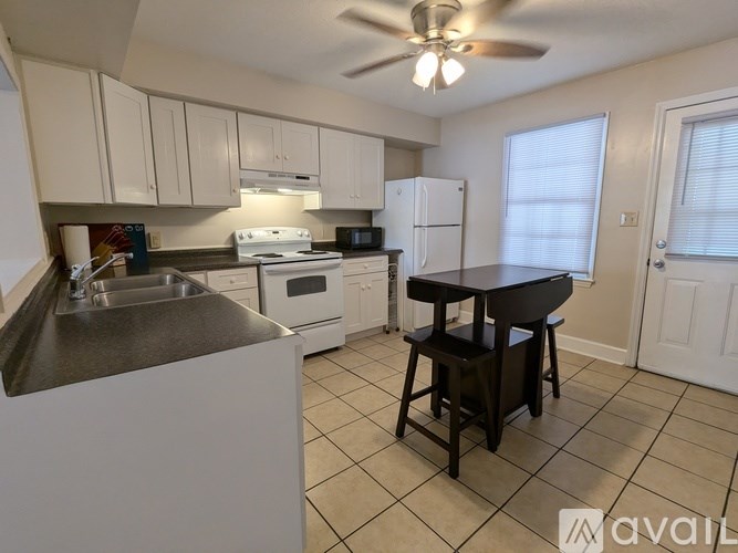 A kitchen with white cabinets and a black table.