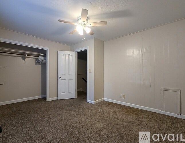 A room with a ceiling fan and a door.