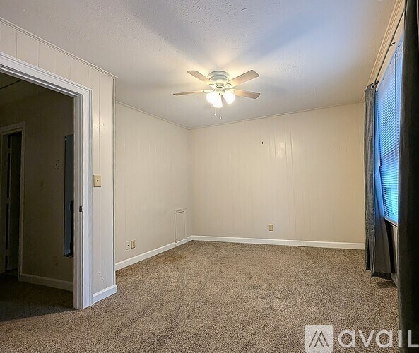 A room with a ceiling fan and carpeted floor.