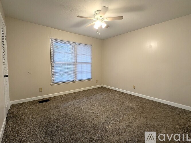 A room with a ceiling fan and a window with blinds.