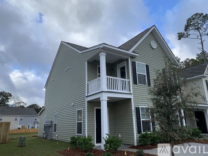 A house with a balcony and a tree in front.