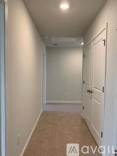 A long, narrow hallway with a carpeted floor and white walls.