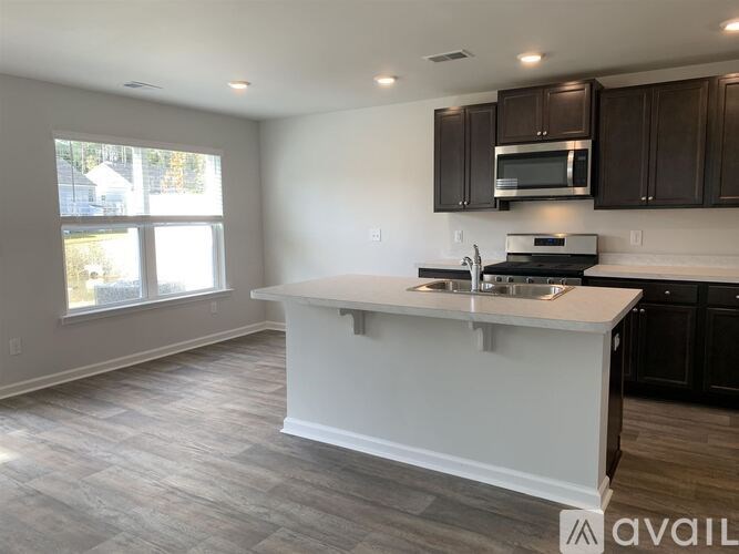 A kitchen with a white island and dark brown cabinets.