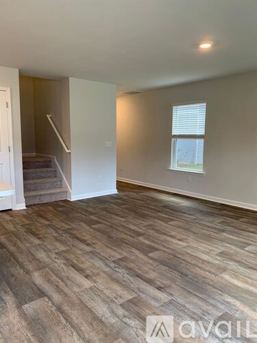 A room with wooden flooring and a window with blinds.