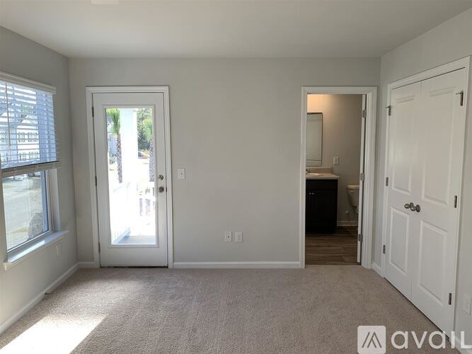 A room with a carpeted floor and a door leading outside.