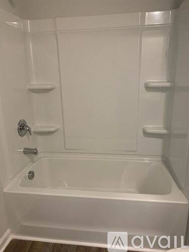 A white bathtub with a shower head and faucet.