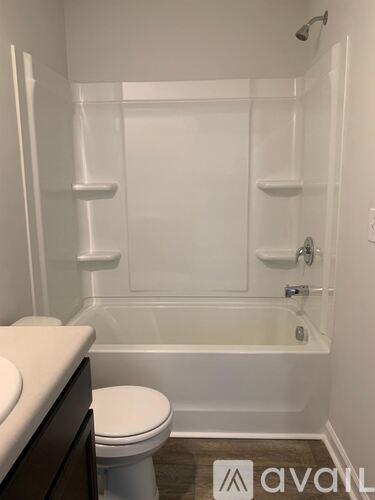 A white toilet sits next to a bathtub in a bathroom.