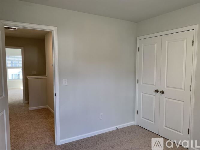 A room with a white door and carpeted floor.