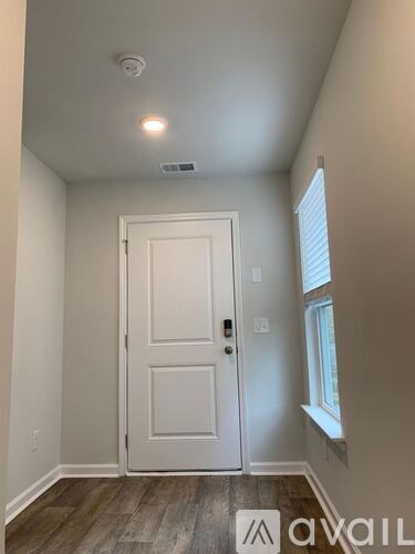 A white door is in a room with a window to the right.