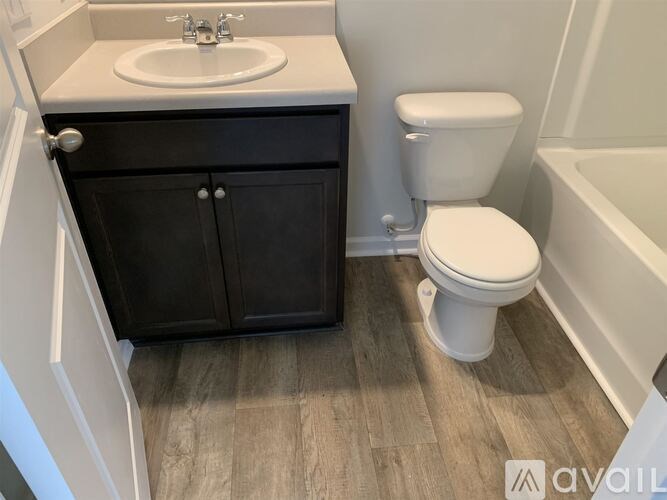A bathroom with a white toilet and a sink with a cabinet underneath it.