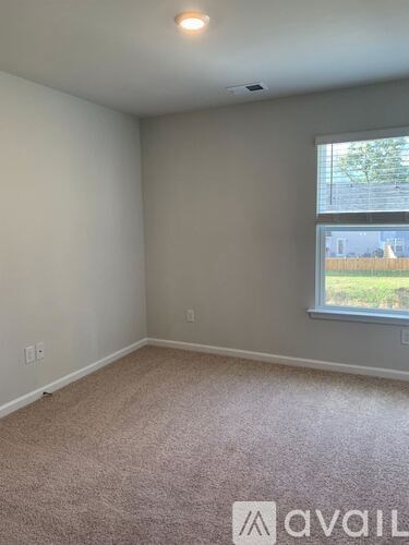 A room with a window and a carpeted floor.