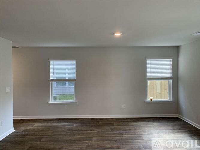 A room with wooden floors and two windows.