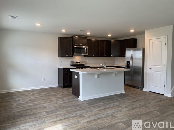 A kitchen with a white island and dark brown cabinets.