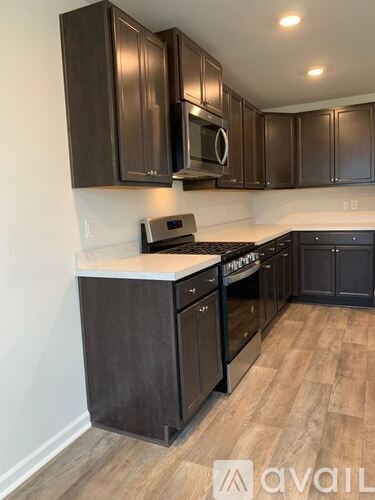 A kitchen with dark brown cabinets and a white countertop.