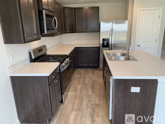 A kitchen with black cabinets and a stainless steel refrigerator.