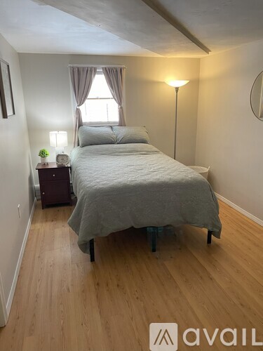 A bedroom with a bed, nightstand, and lamp.