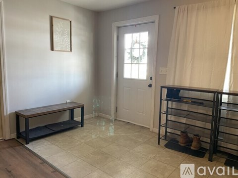 A room with a bench, a door, and a picture on the wall.