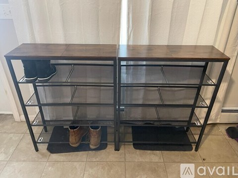 A black shoe rack with two pairs of shoes on it.