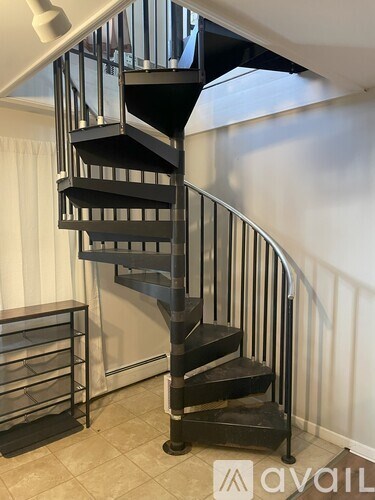 A black metal spiral staircase with a white railing.