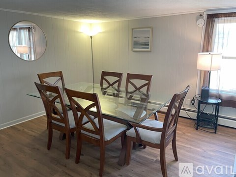 A glass dining table with four chairs and a small side table.