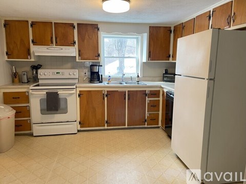 A kitchen with white appliances and wooden cabinets.