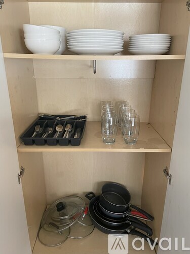 A kitchen cabinet with plates, bowls, and glasses.