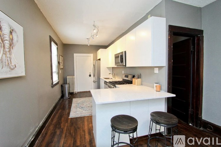 A kitchen with white cabinets and a white island with two stools.