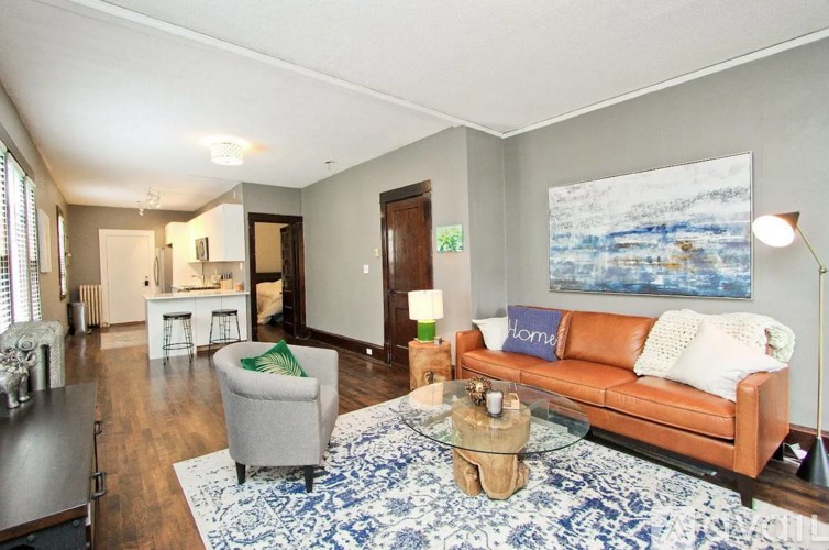 A living room with a brown couch and a blue and white rug.