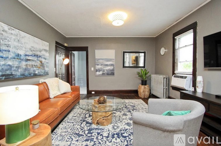 A living room with a brown couch, a glass coffee table, and a large painting on the wall.