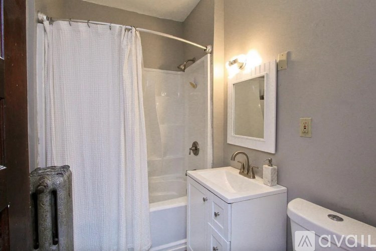 A white bathroom with a toilet, sink, and shower.