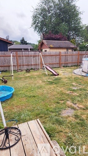 A backyard with a wooden fence and a blue pool.