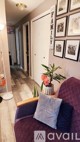 A living room with a purple couch and a wall with pictures and a sign that says "FAMILY".