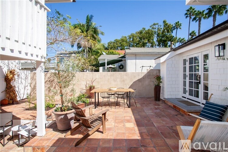 A patio with a table and chairs is surrounded by a white wall and a white building.