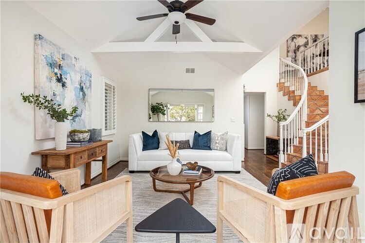 A living room with a white couch and wooden furniture.