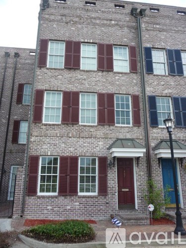 A brick building with a red door and a lamp post in front.