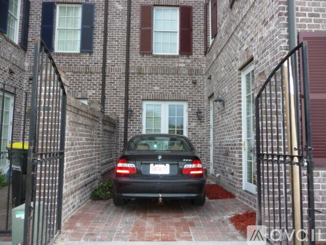 A black car is parked in a brick alleyway.