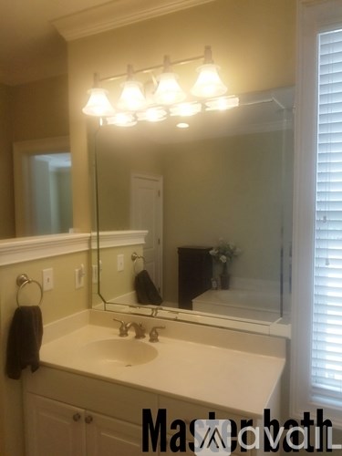 A bathroom with a sink, mirror, and lights.