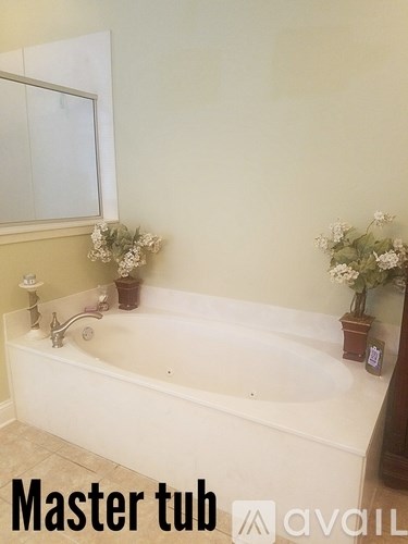 A white bathtub with a faucet and a vase of flowers.