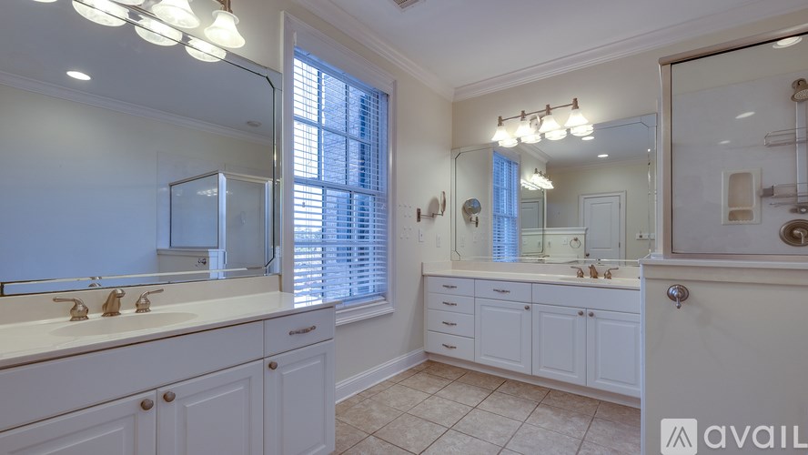 A bathroom with a large mirror, double sinks, and a window with blinds.