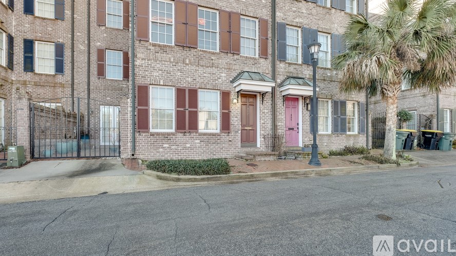 A brick building with a red door and a palm tree in front.