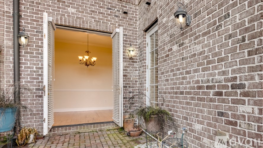 A brick wall with a doorway leading to a room with a chandelier.
