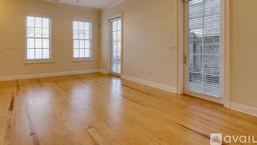 A room with wooden flooring and two windows.