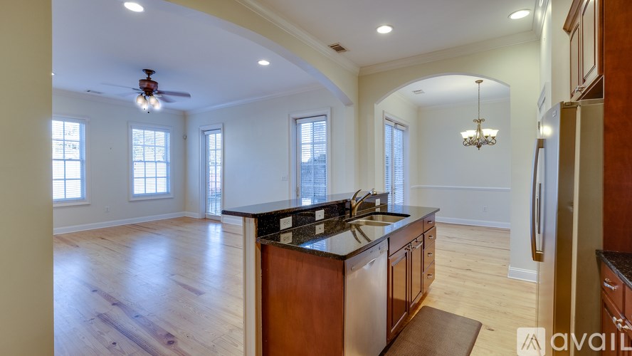 A kitchen with wooden floors and a central island with a stove top oven.