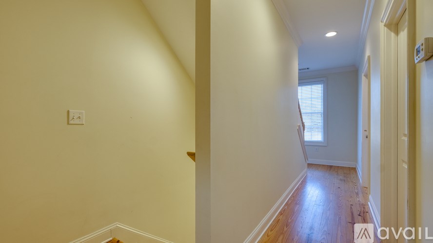 A hallway with wooden floors and white walls.