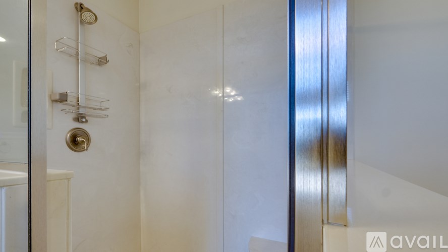 A bathroom with a glass shower door and a metallic door handle.