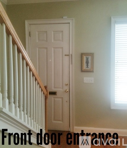 A white door with a wooden frame and a picture on the wall above it.