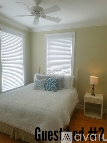 A bedroom with a bed, a fan, and a lamp.