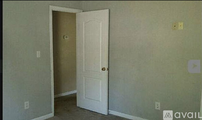 A white door is open to a room with a wall and a switch.